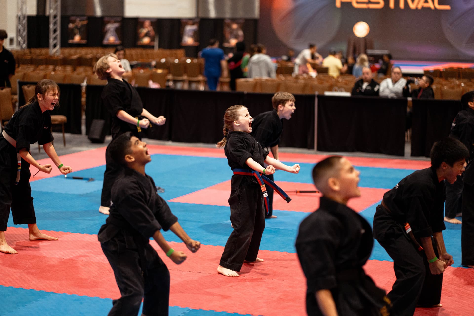 Young martial artists training together on the competition floor at IMAF